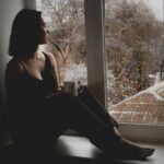 person sitting window rain looking out thoughtful