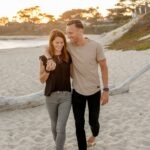 happy mature couple walking beach laughing