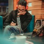 person reading book couch headphones
