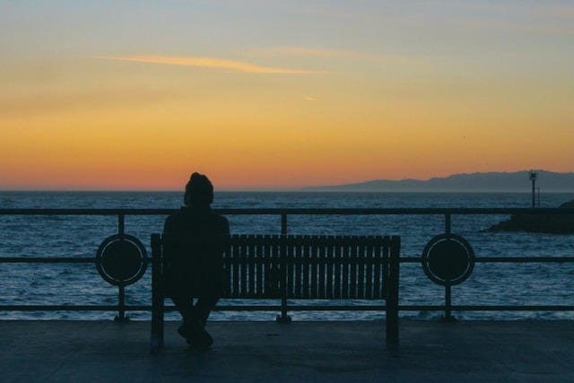lonely person sitting bench sunset silhouette