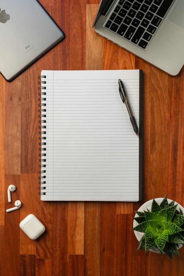 An image of a notebook and pen on a desk