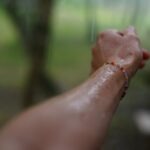 person hand touching glass pane rain outdoors