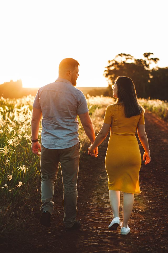 couple holding hands walking nature path sunset