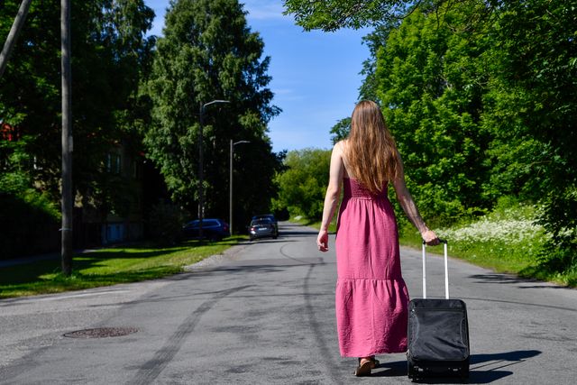 person walking away with suitcase road
